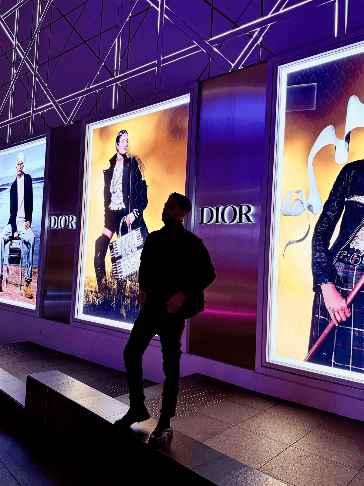 Person walking through a neon-lit DIOR corridor